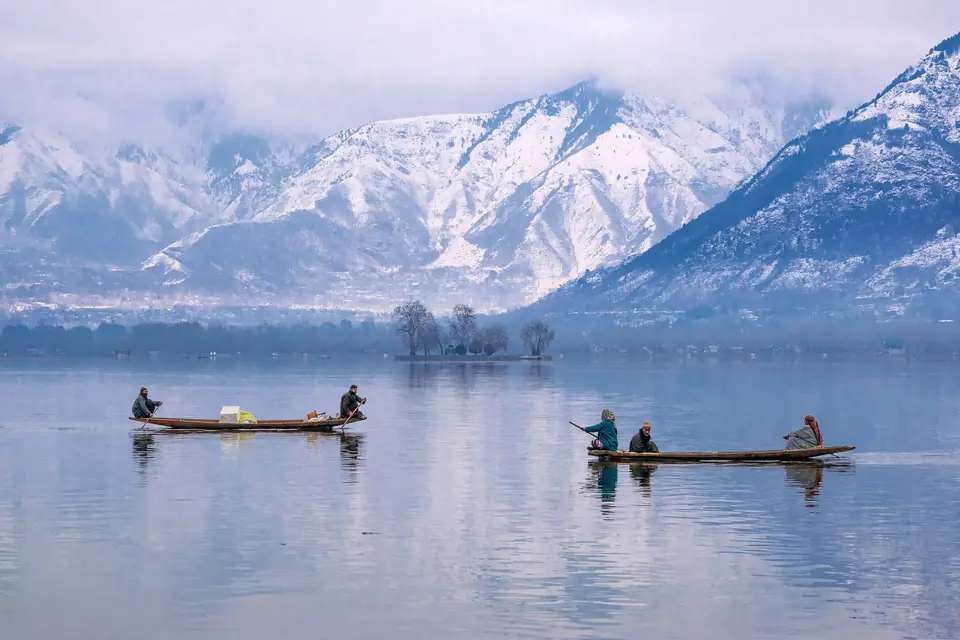 Shikaras crossing Dal Lake below snow-covered mountains
