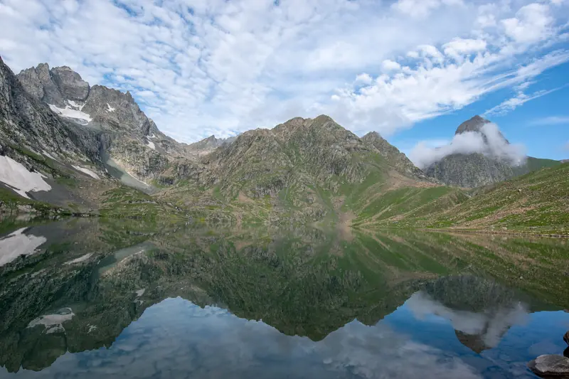 Vishansar Lake reflecting the surrounding peaks on the Great Lakes trek